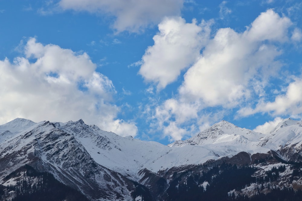 a snow covered mountain range under a cloudy blue sky