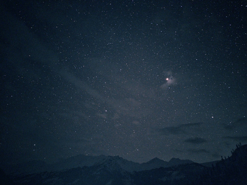 the night sky with stars above a mountain range