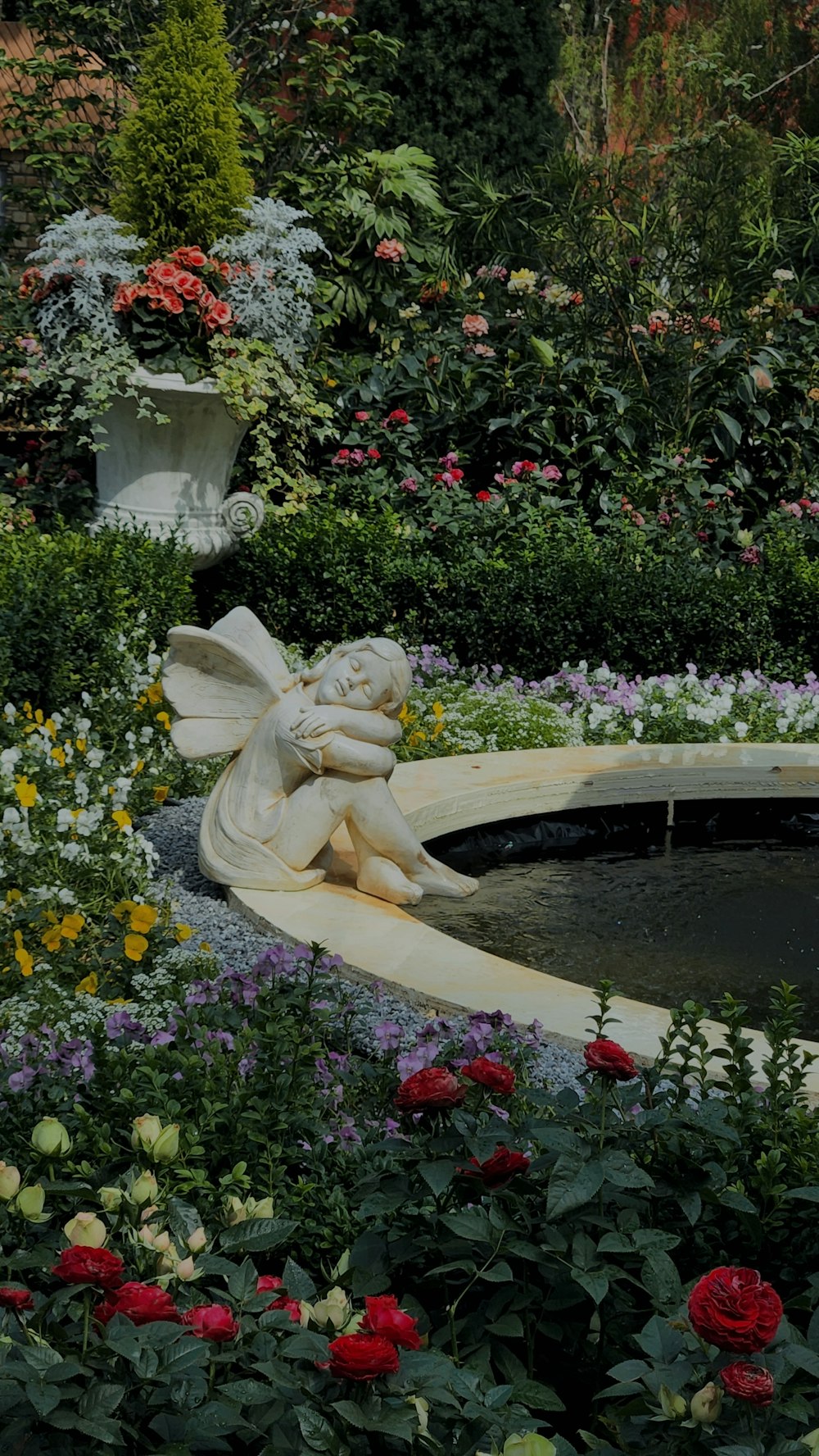 ein Garten mit vielen Blumen und einer Statue