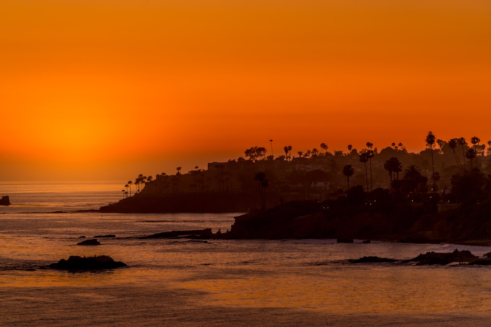 the sun is setting over the ocean with a city in the distance