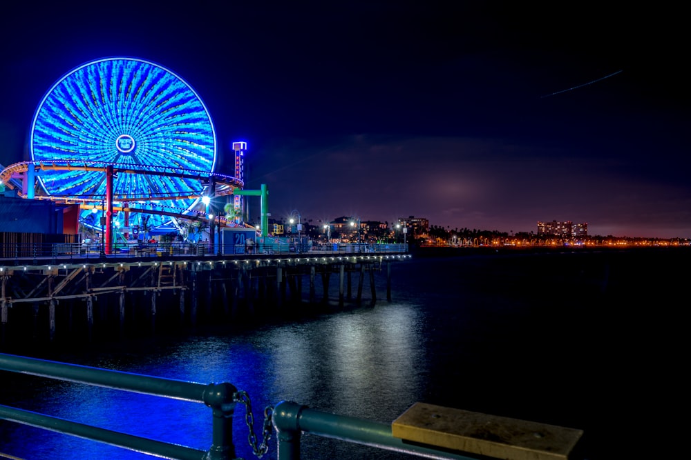 a ferris wheel lit up at night by the water