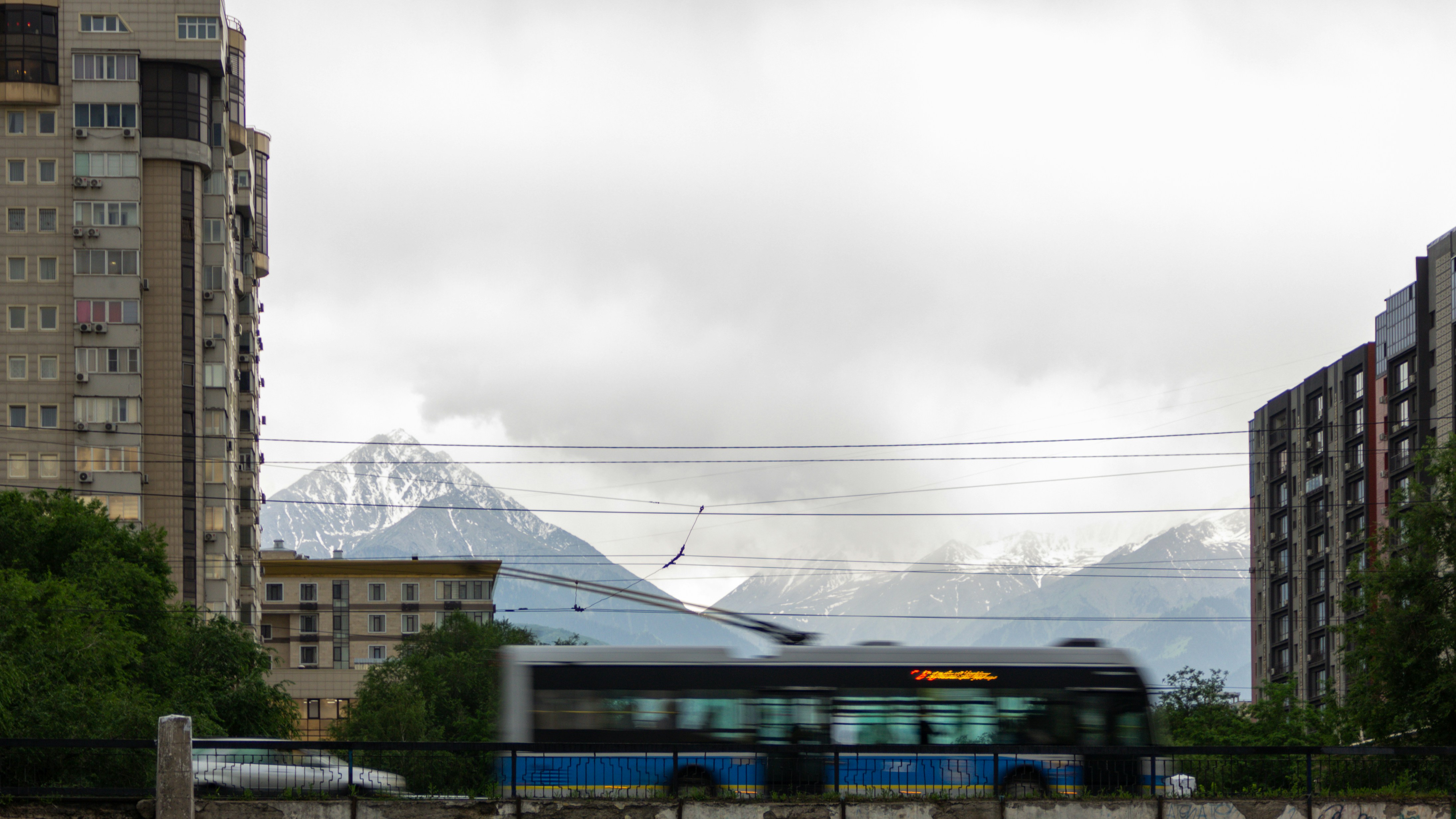 поезд едет по городу мимо высоких зданий