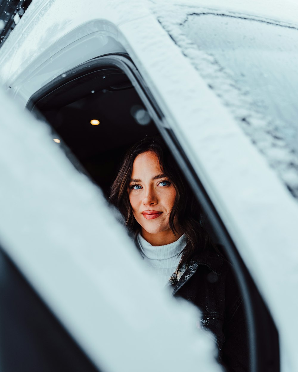 a woman looking out of a car window in the snow