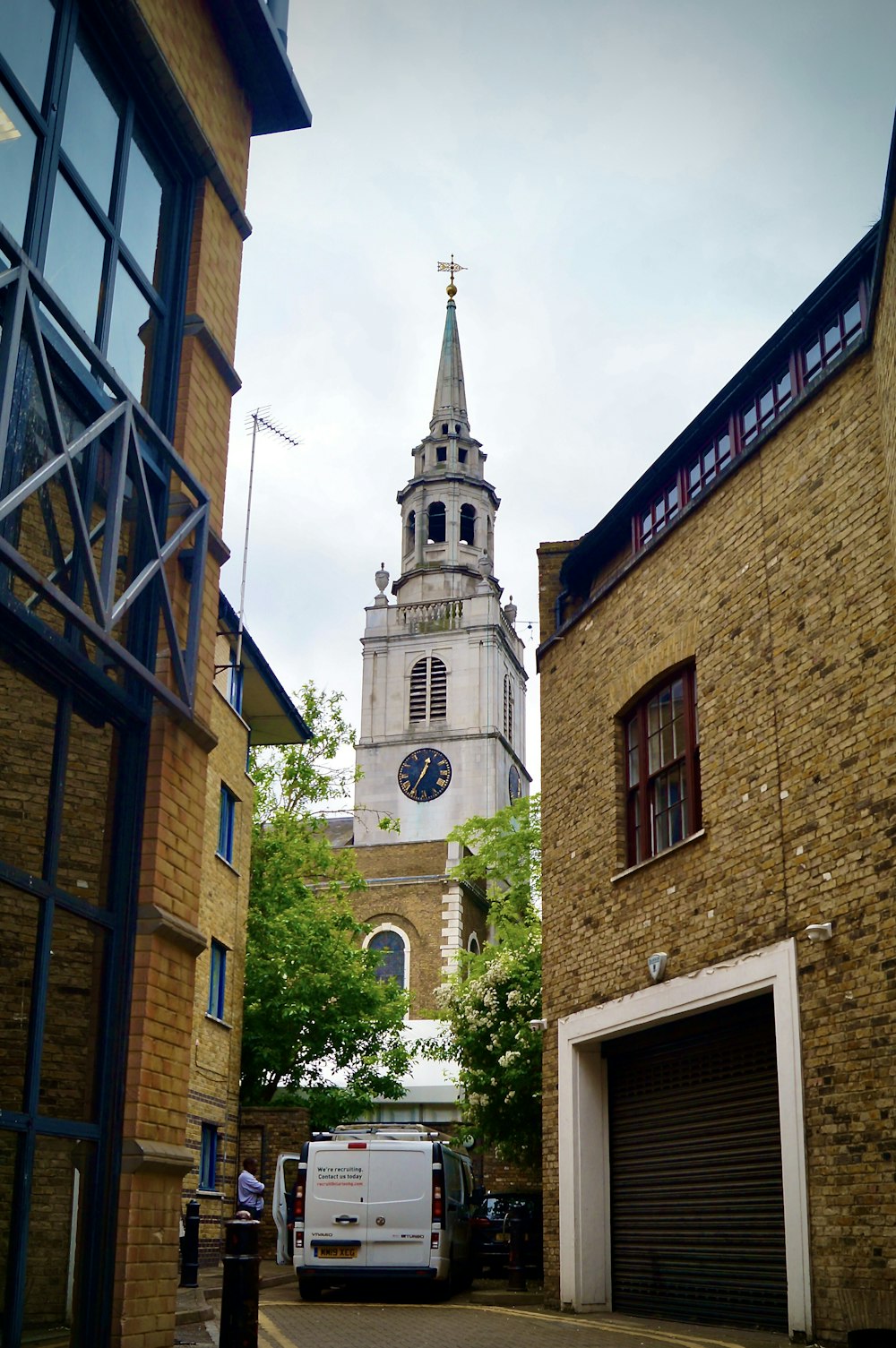 a white van parked in front of a tall clock tower