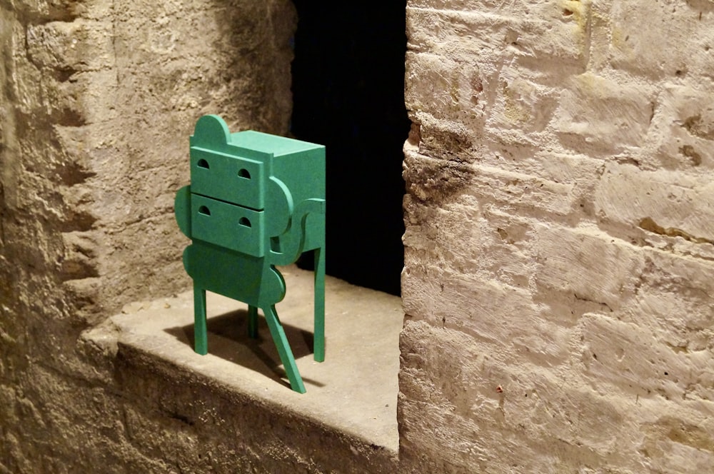 a small green object sitting in a window sill