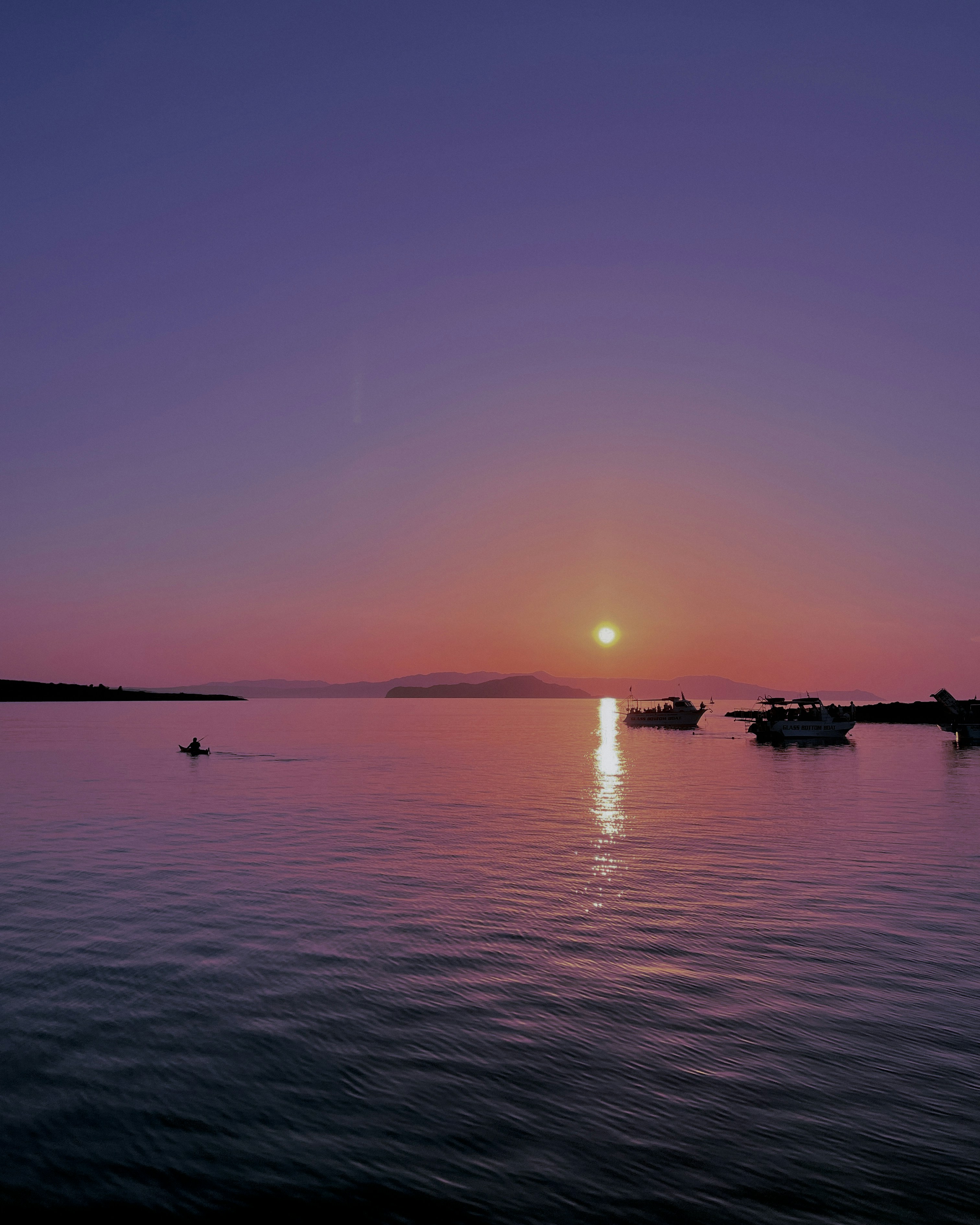 a sunset over a body of water with boats in the water