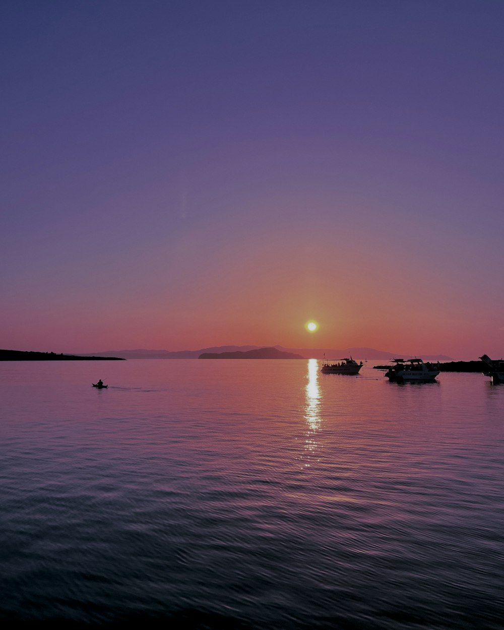 a sunset over a body of water with boats in the water