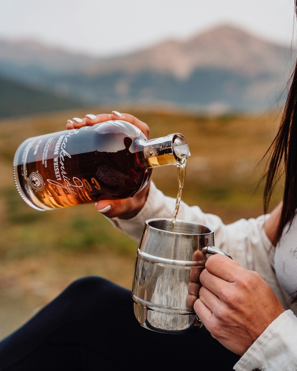 a woman pouring a glass of beer into a bucket