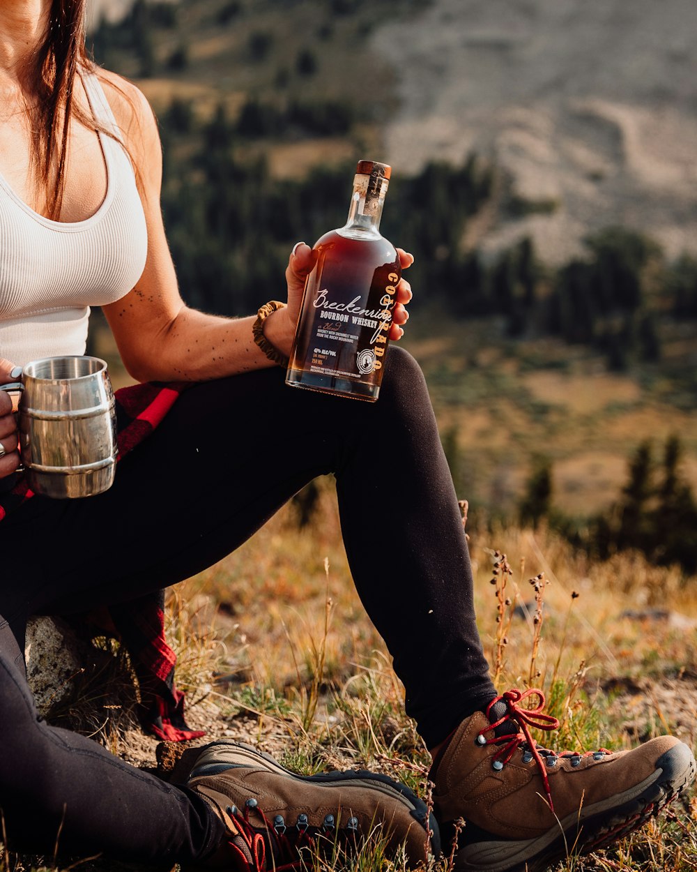 a woman sitting on the ground holding a bottle of whiskey