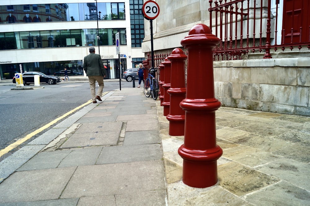 a row of red fire hydrants sitting on the side of a road