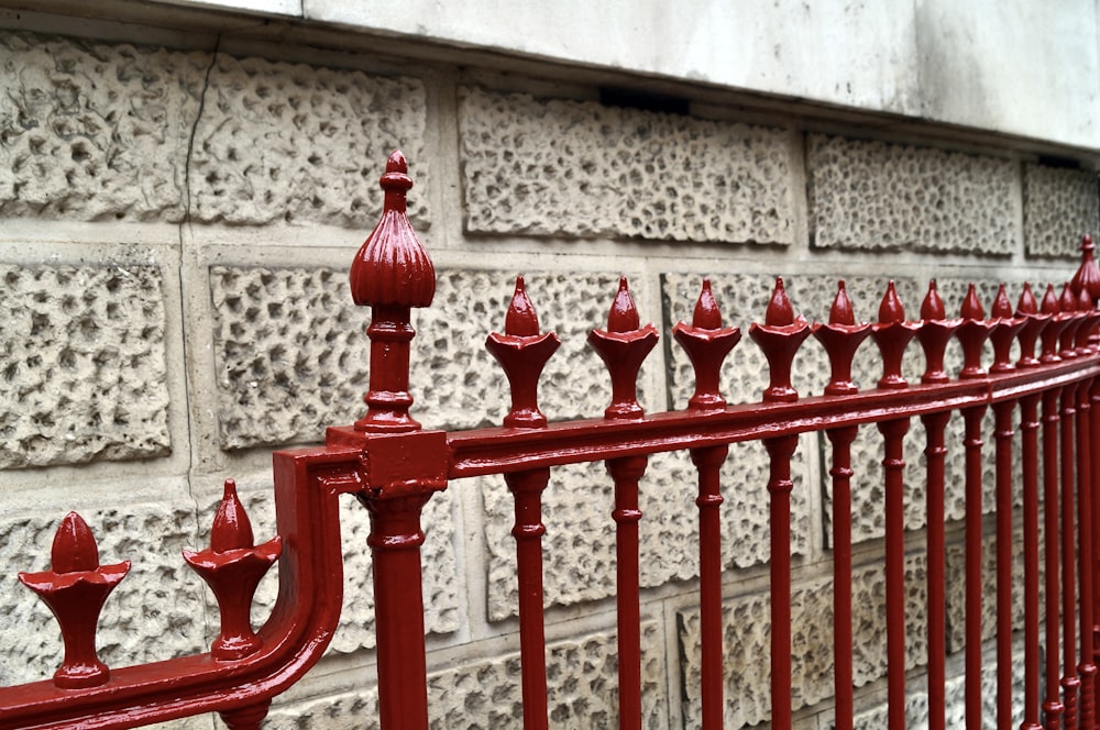 a red metal fence next to a brick wall