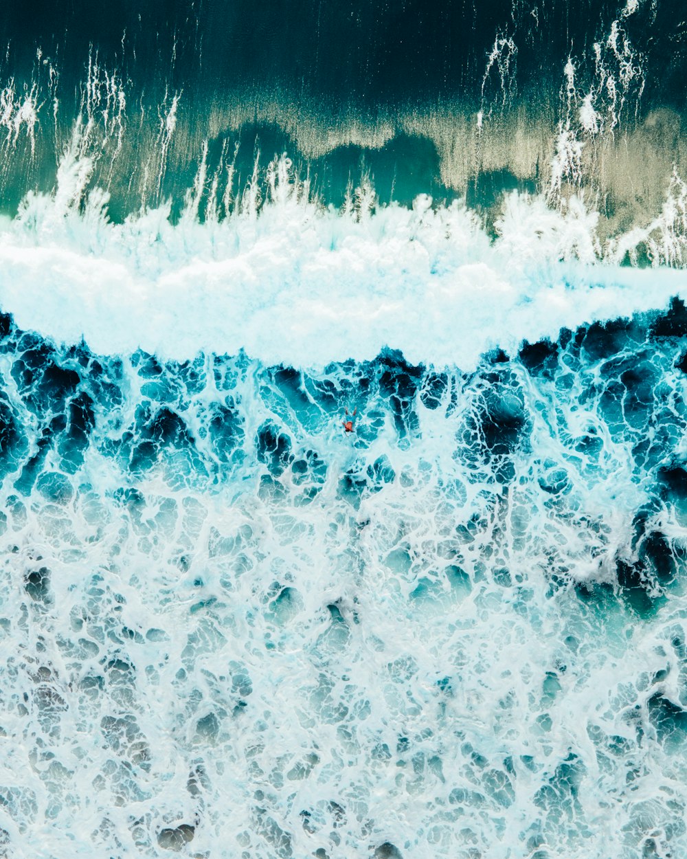 an aerial view of the ocean waves and rocks