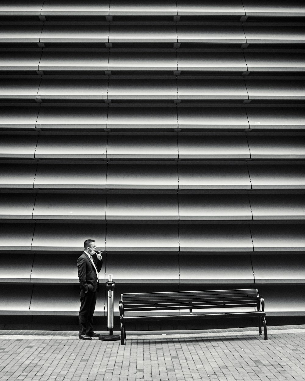 a man standing next to a bench in front of a building