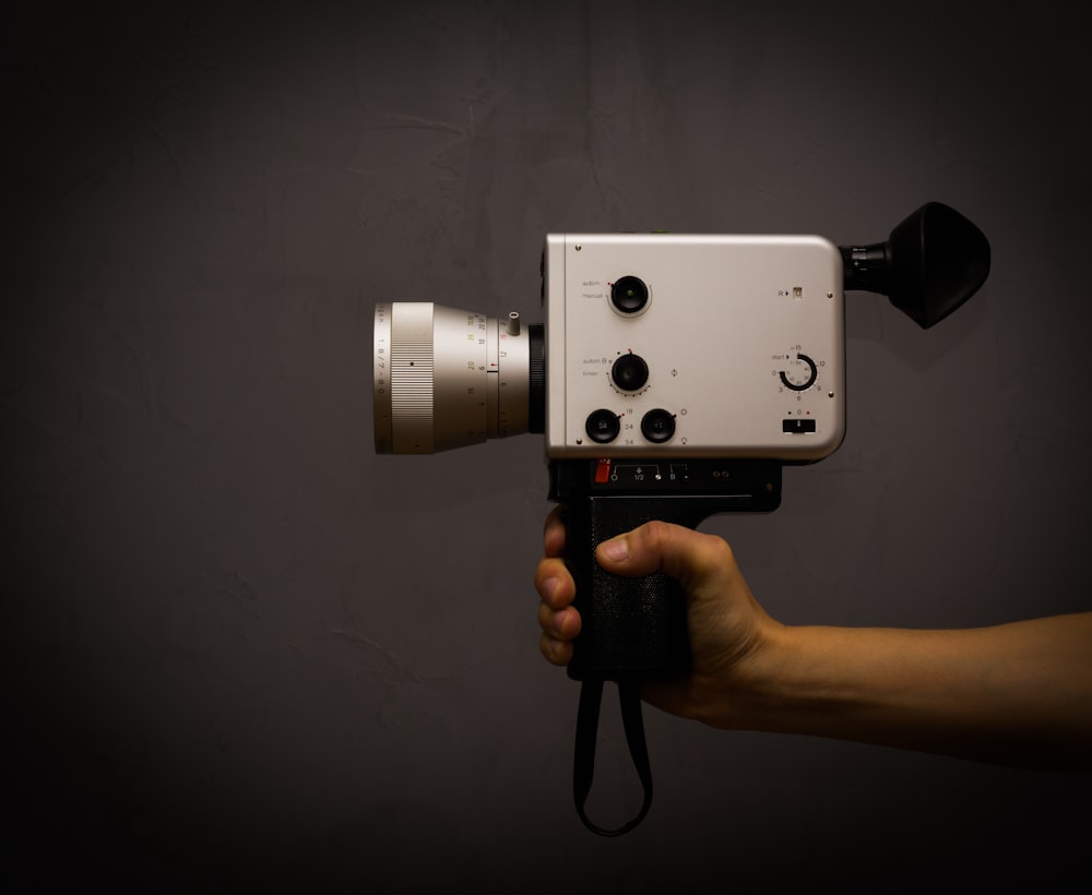 a hand holding a camera with a black background