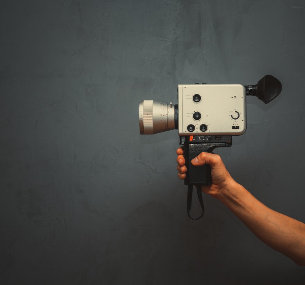 a hand holding a camera with a video camera attached to it