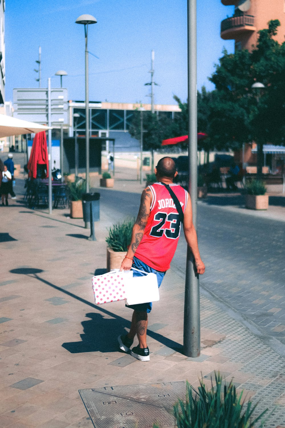 a man in a red jersey is walking down the street