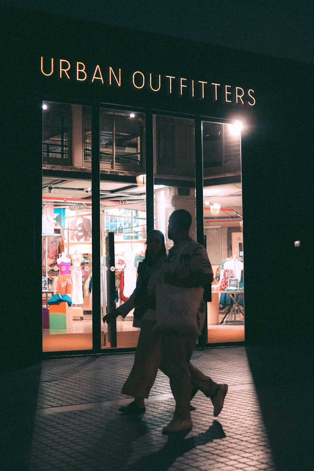 a couple of people that are walking in front of a store