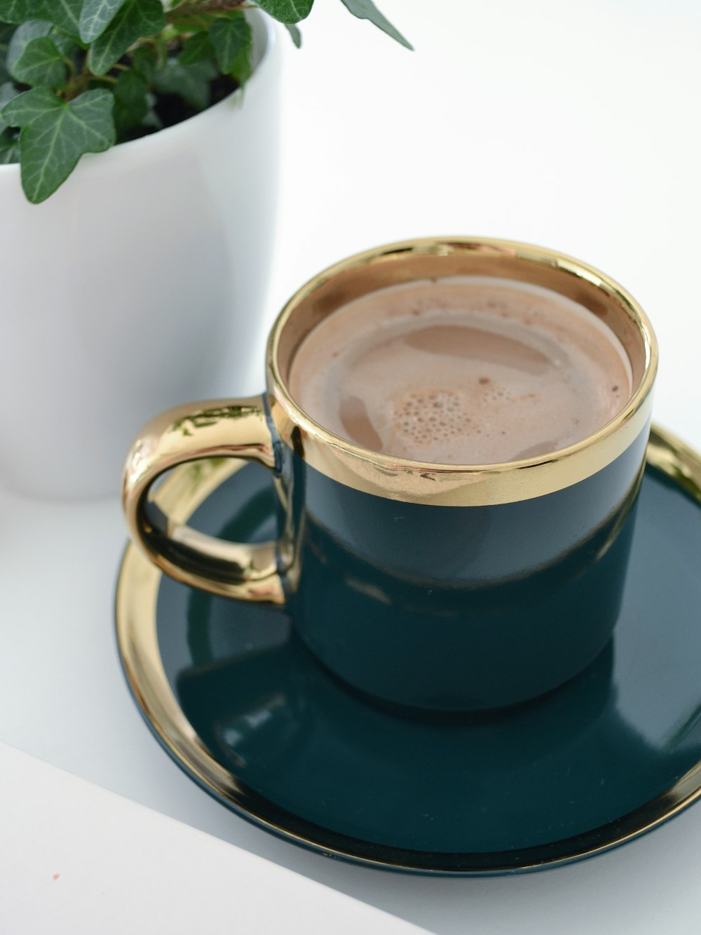 a cup of coffee on a saucer next to a potted plant