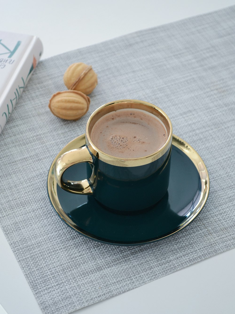 a cup of coffee on a saucer next to a book