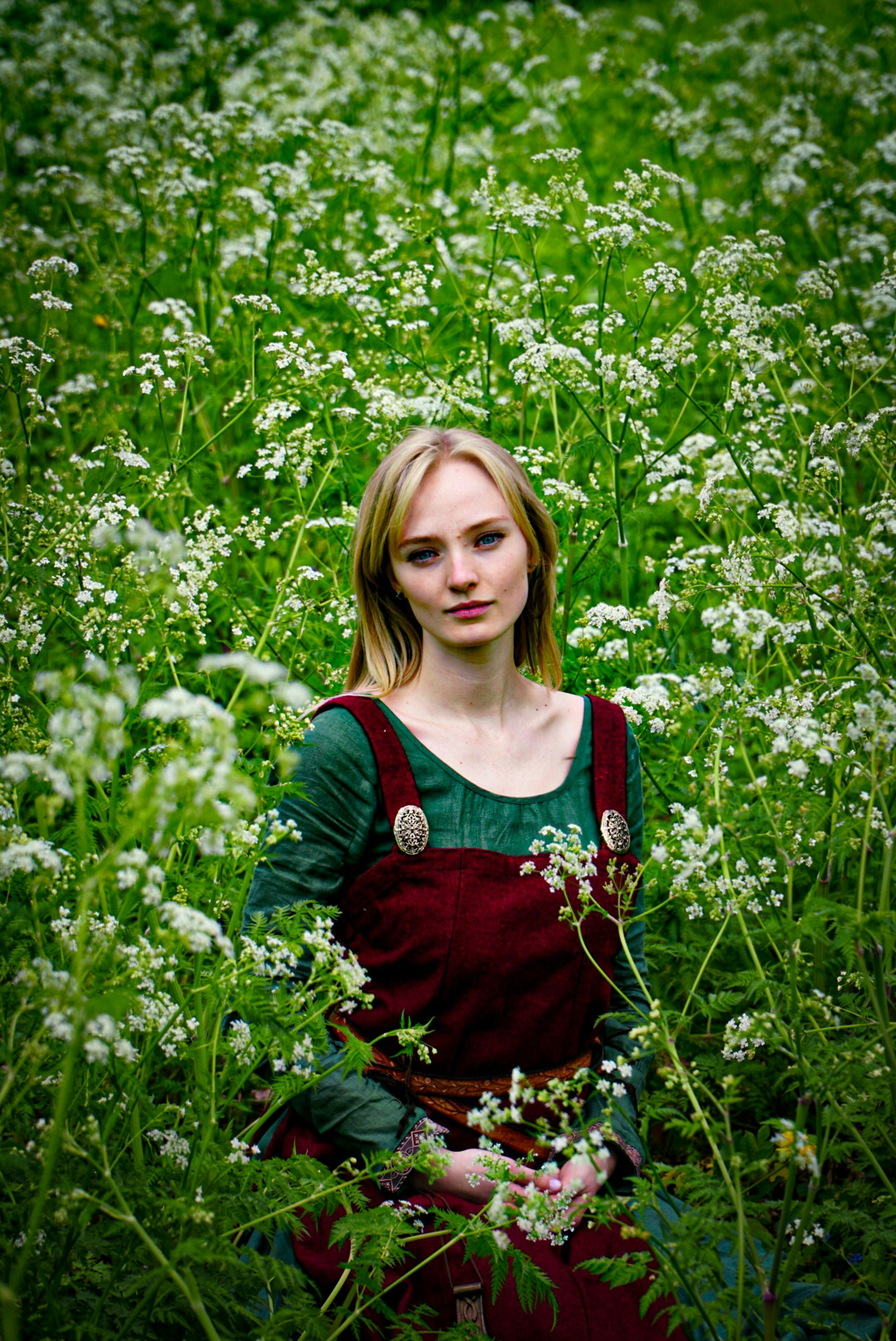 a woman is sitting in a field of flowers
