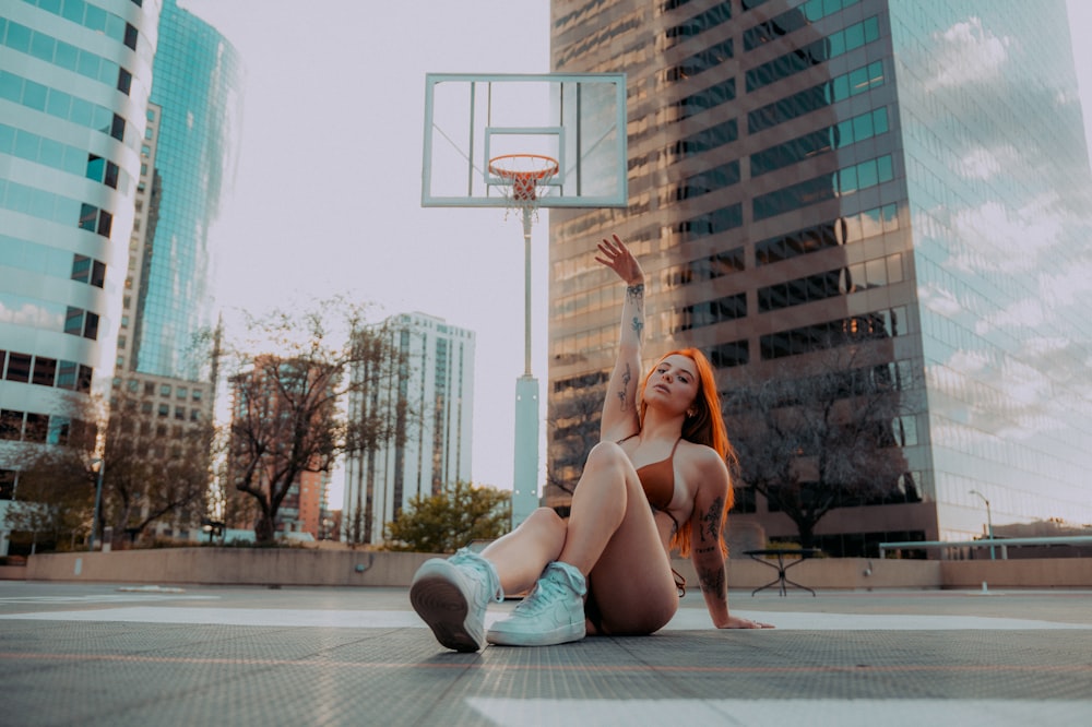 a woman sitting on the ground in front of a basketball hoop