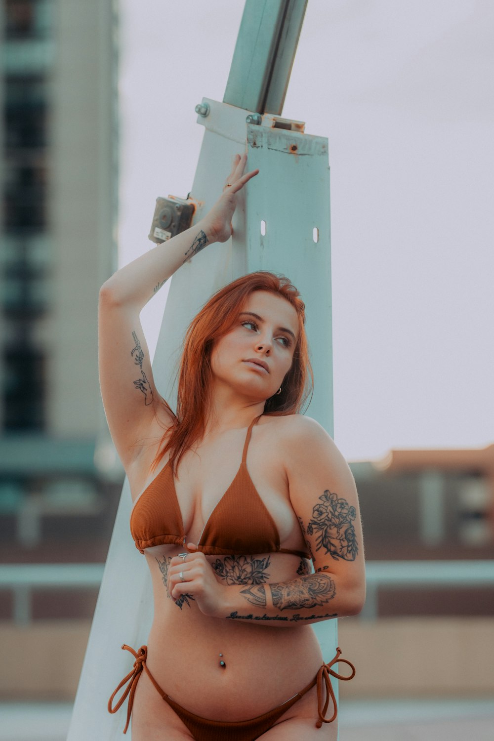 a woman in a bikini leaning against a pole