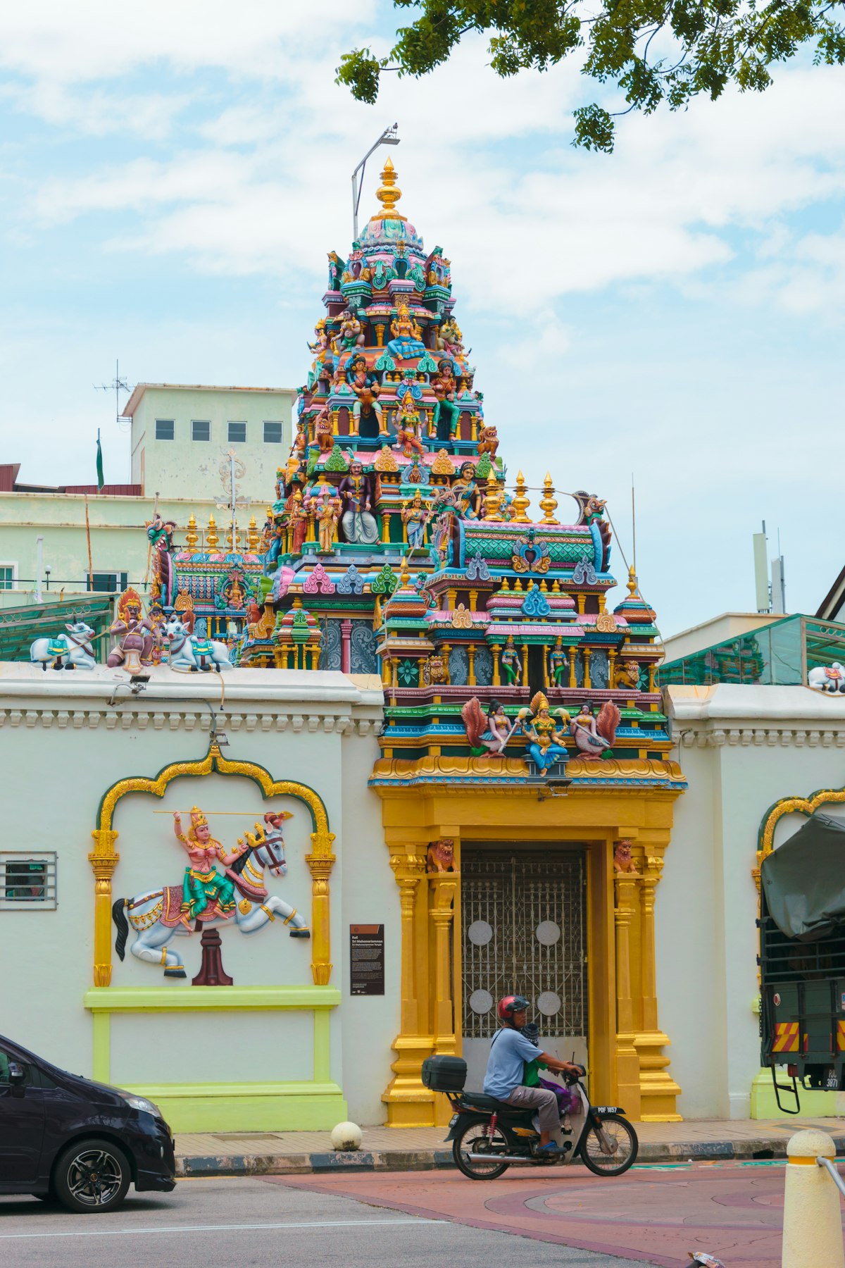 A man riding a motorcycle past a colourful building in Penang
