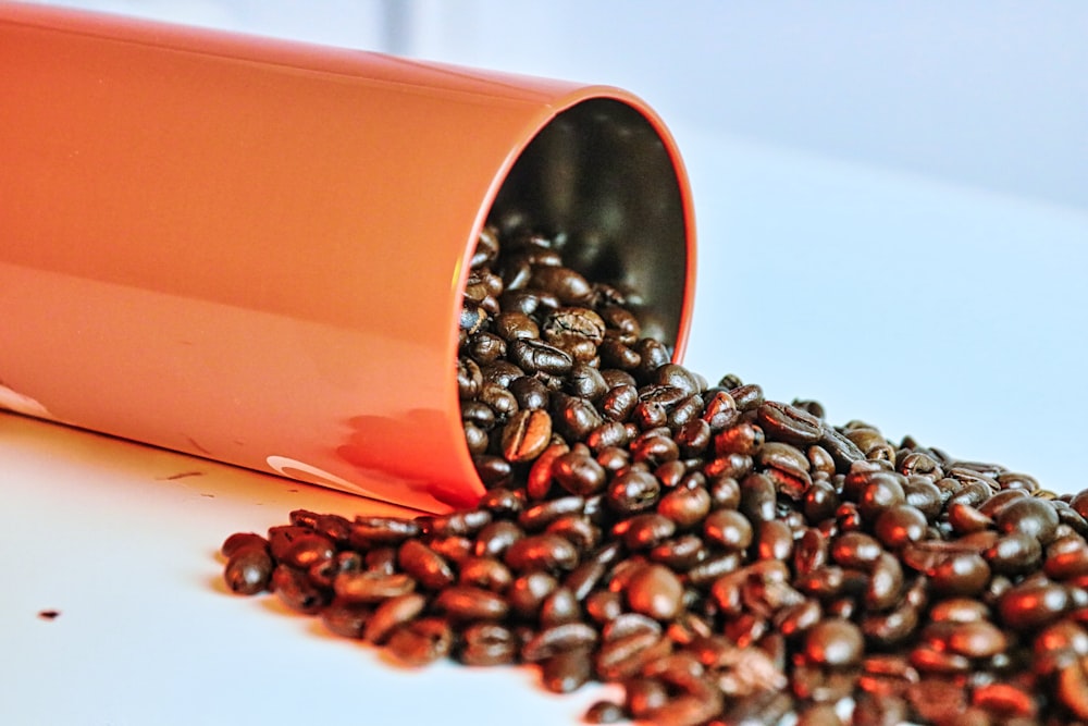 a pile of coffee beans spilling out of a cup