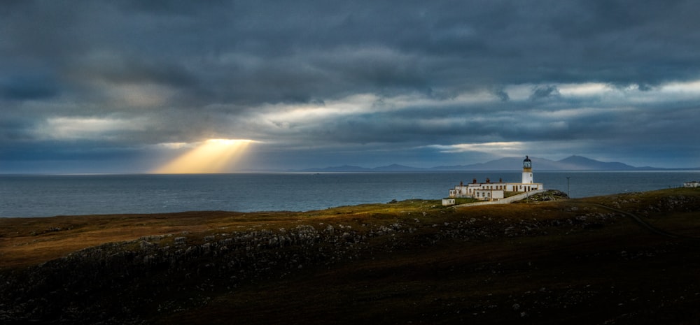 a lighthouse on a hill with a cloudy sky