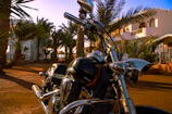 A sleek, shiny motorcycle parked outside Varsha Velocity showroom on a sunny day.
