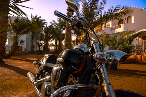 A sleek, shiny motorcycle parked outside Varsha Velocity showroom on a sunny day.