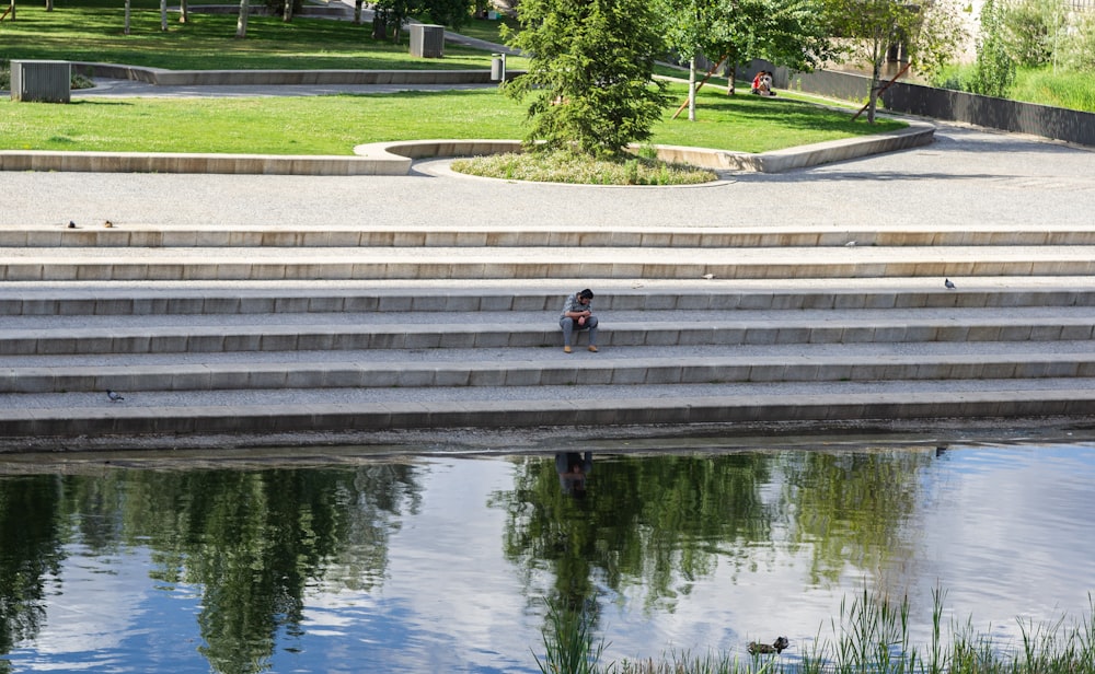 a person sitting on some steps next to a body of water