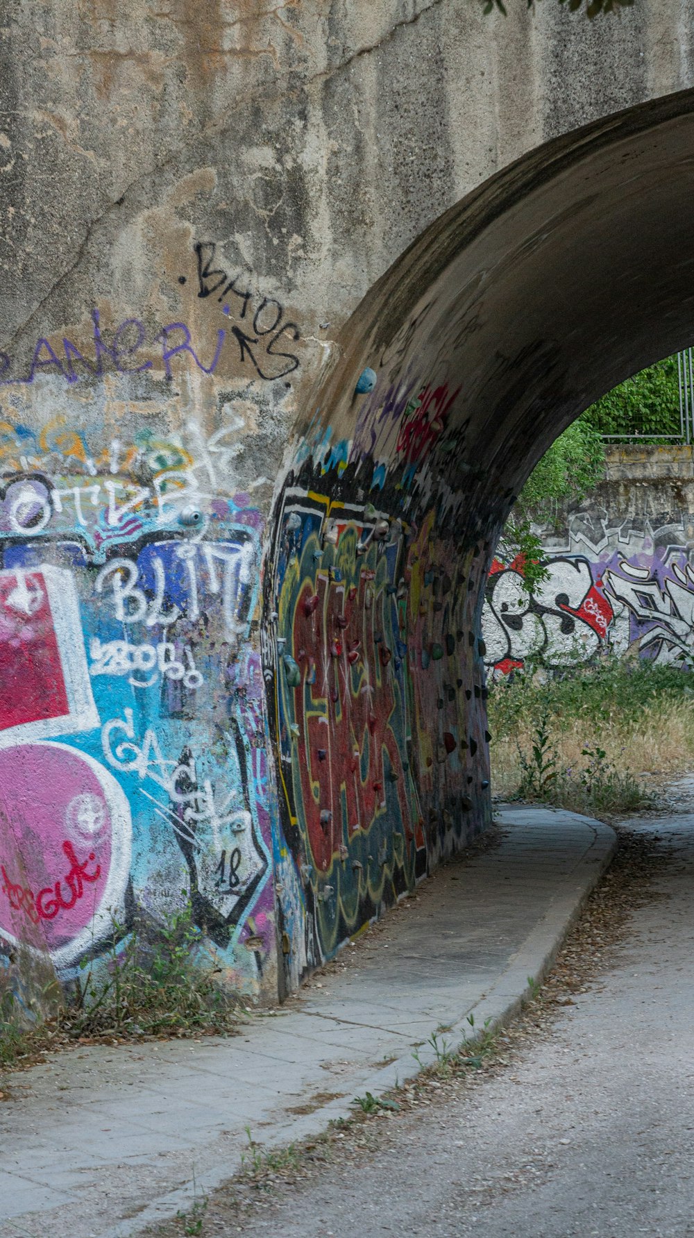 Un uomo che cavalca uno skateboard sotto un ponte coperto di graffiti