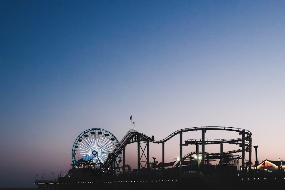 a roller coaster and a ferris wheel at dusk