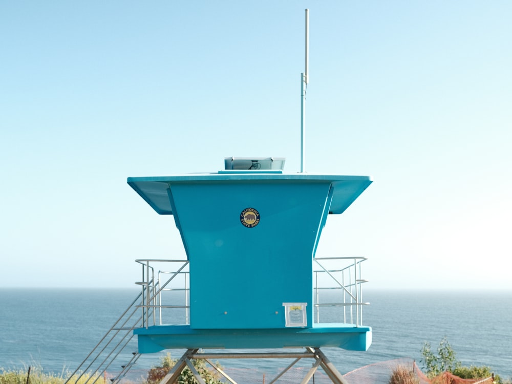 a blue lifeguard tower sitting on top of a hill