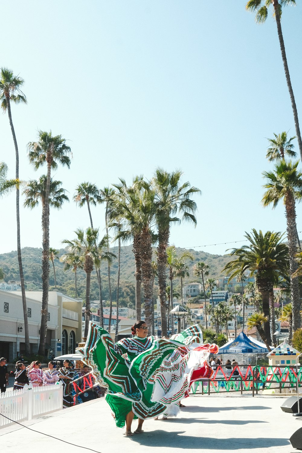 a woman in a green dress dancing in front of palm trees