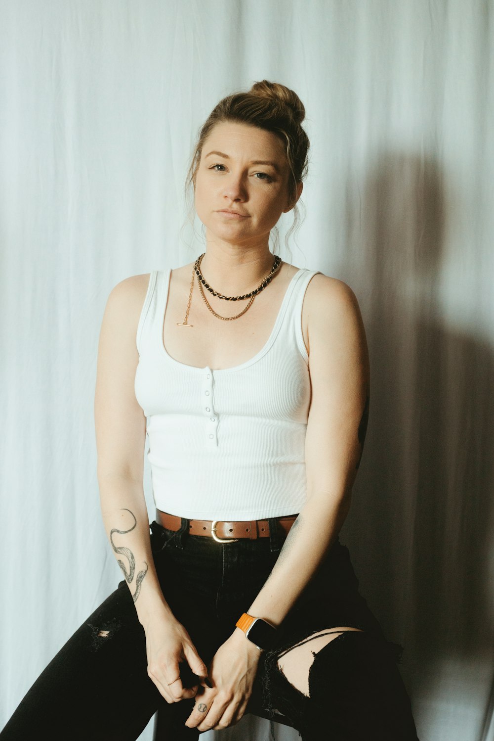 a woman in a white tank top sitting on a chair