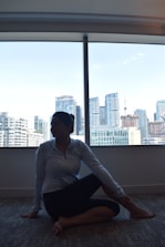 An executive practicing mindfulness meditation in a serene office space overlooking a city skyline.