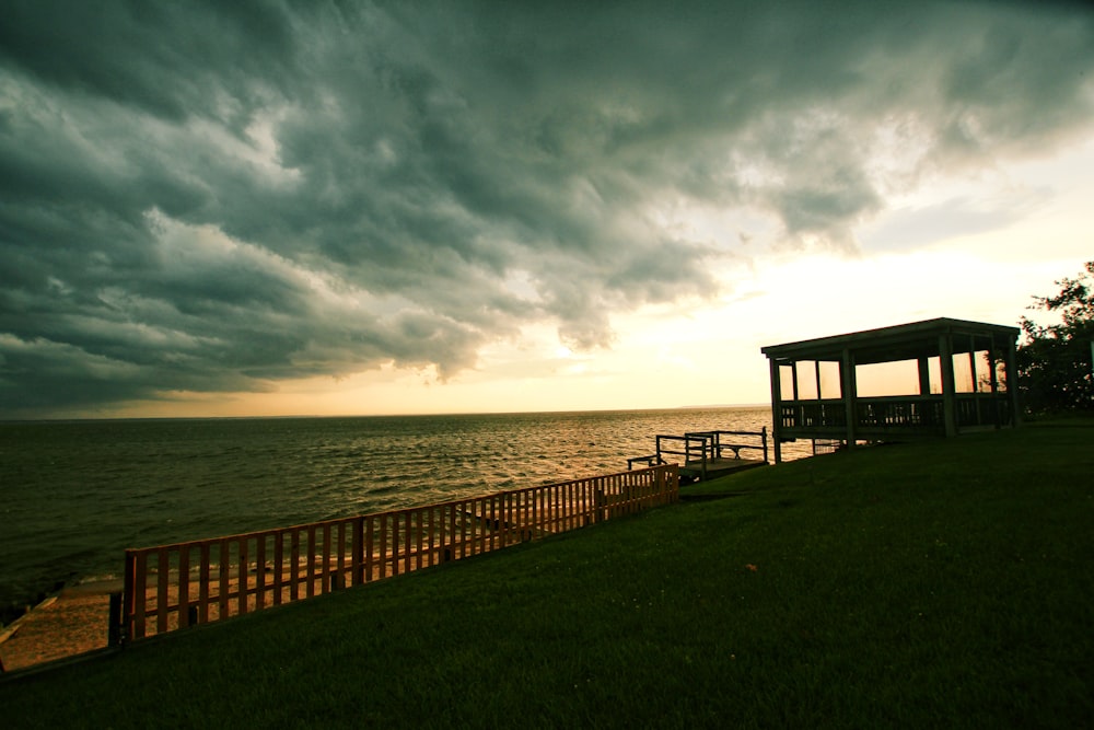 a gazebo sitting on top of a lush green field next to the ocean