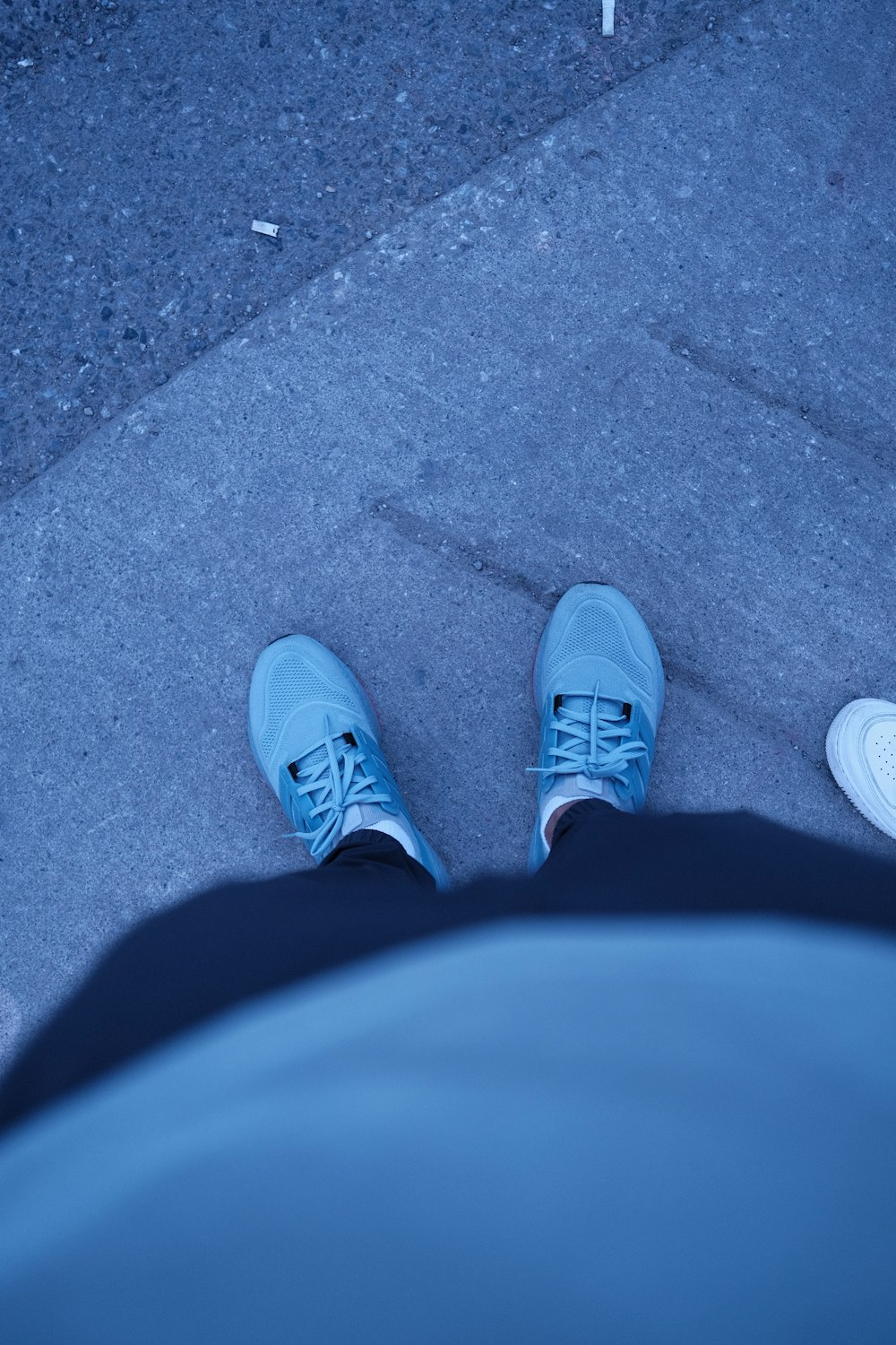 a person wearing blue shoes standing on a sidewalk