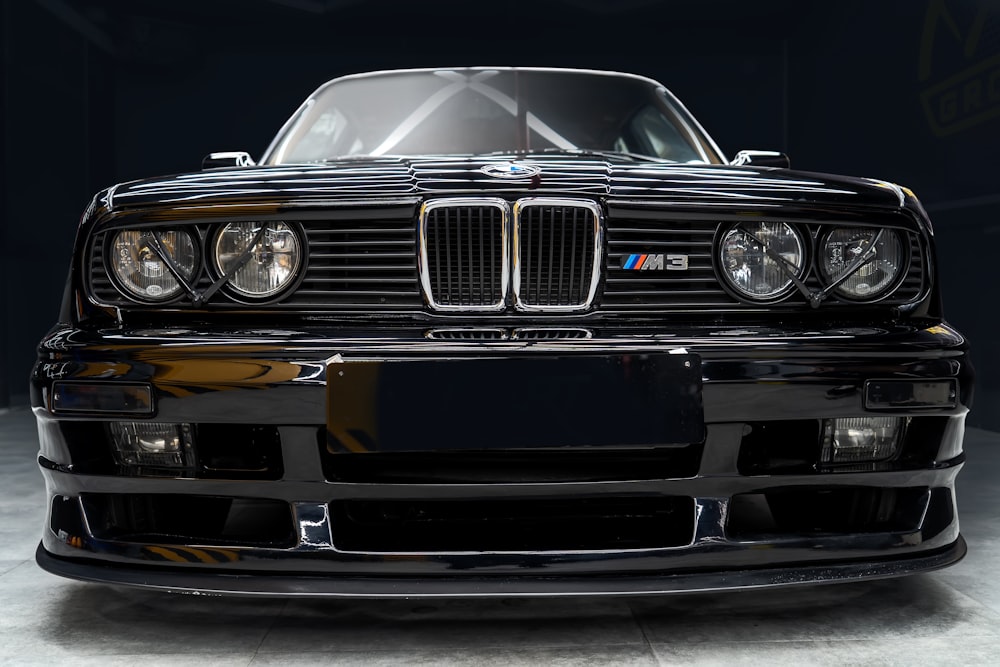 the front of a black bmw car in a dark room