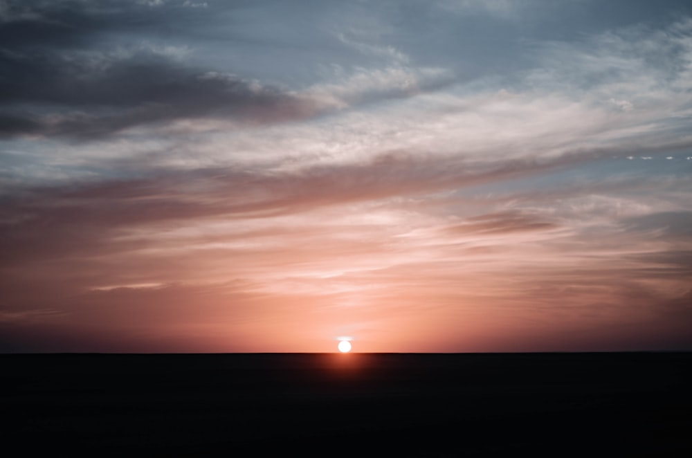 the sun is setting over the horizon of a field