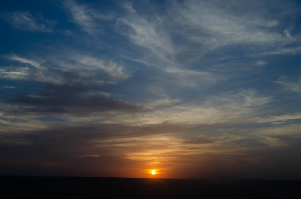 the sun is setting over the horizon of the ocean