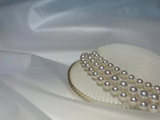 Close-up of a handcrafted pearl necklace resting on natural linen fabric, highlighting delicate craftsmanship.