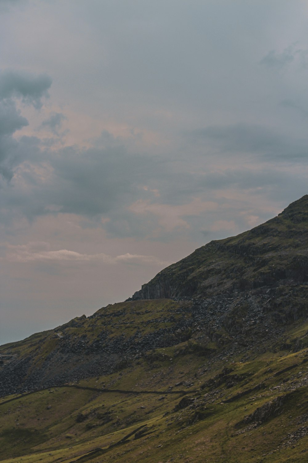 a lone sheep standing on the side of a hill