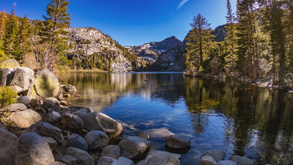 um lago de montanha cercado por rochas e árvores