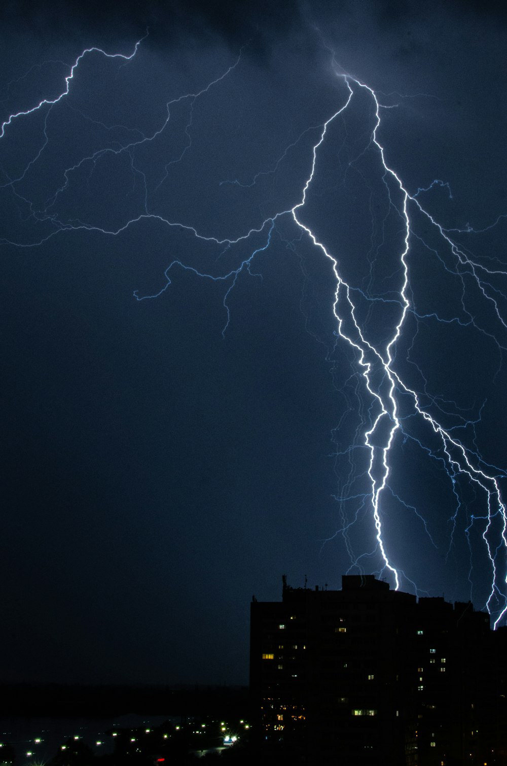 a lightning bolt strikes over a city at night