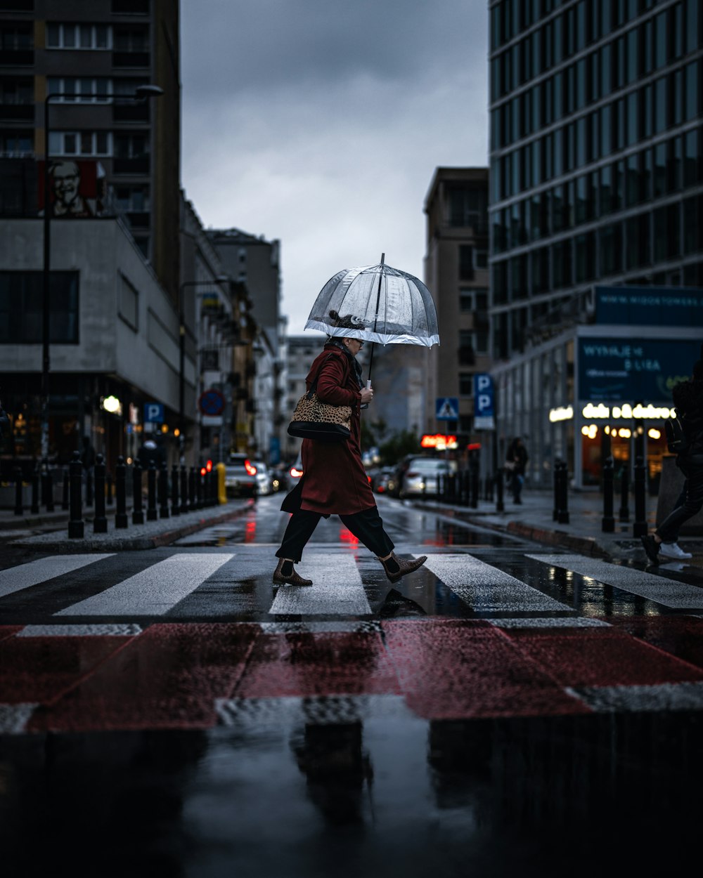 a person walking across a street holding an umbrella
