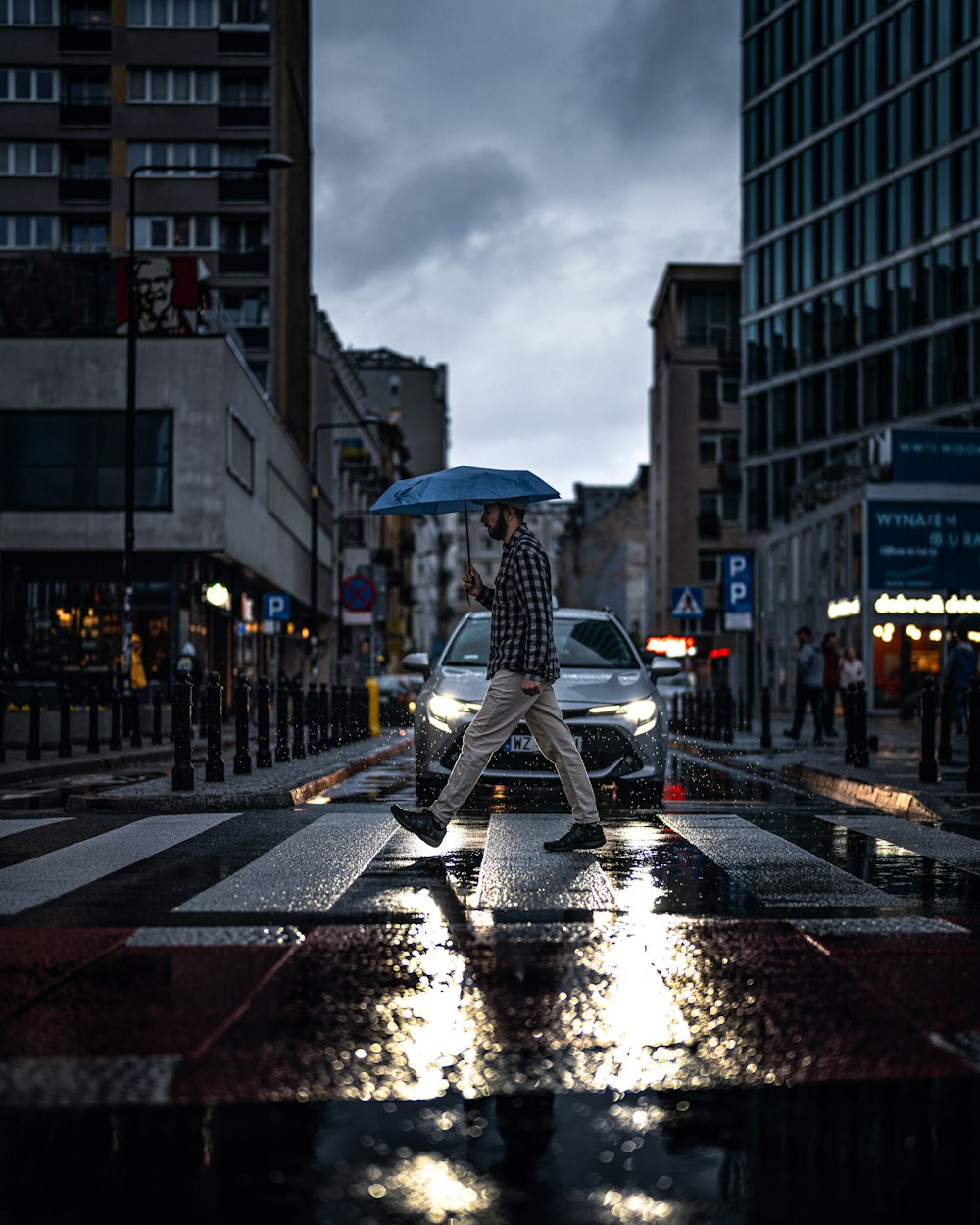 a man walking across a street holding an umbrella