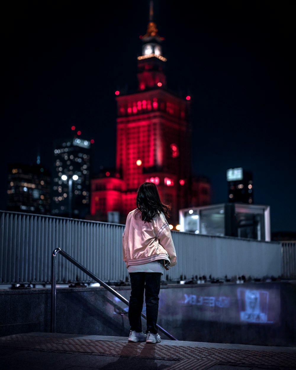 a woman standing on a ledge in front of a building